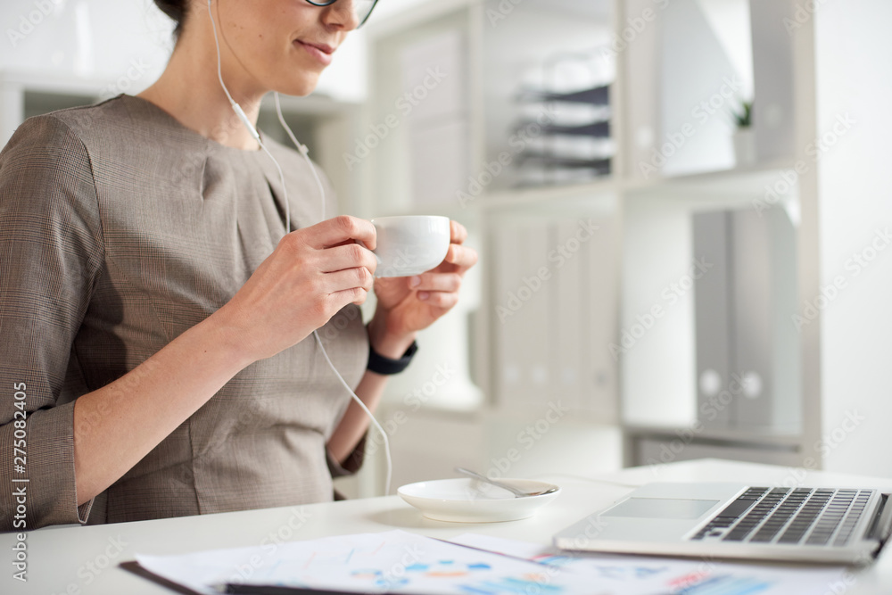 Mad age businesswoman drinking tea in front of a laptop in the office Mad age businesswoman drinking tea in front of a laptop in the office