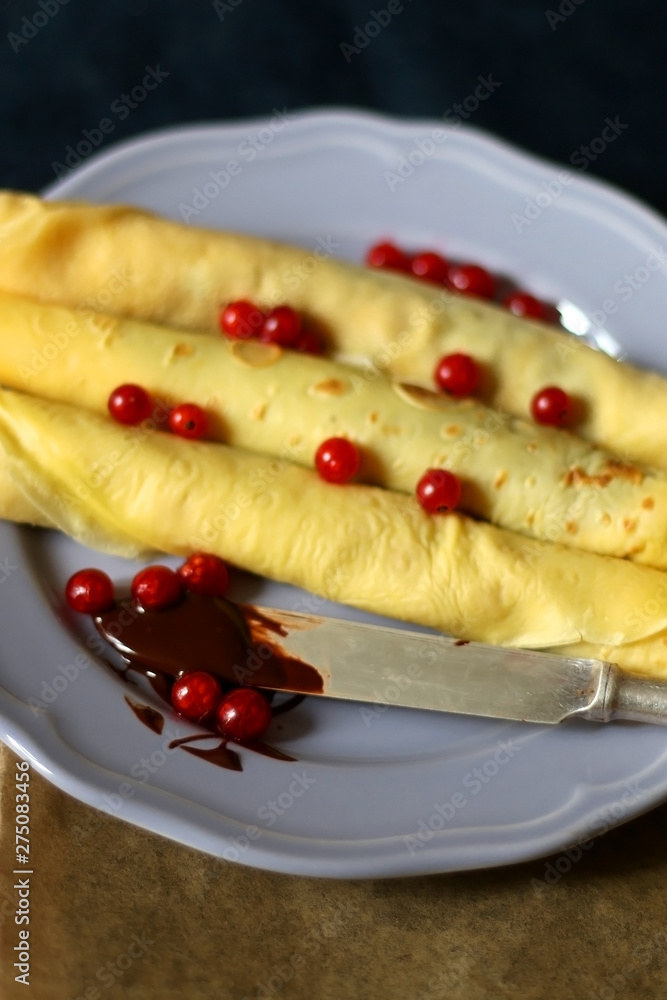 Homemade rolled crepes with chocolate spread and red currants. Selective focus. Homemade rolled crepes with chocolate spread and red currants. Selective focus.