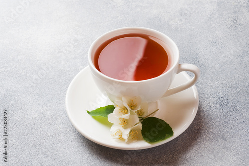 Cup of tea with Jasmine flowers on a gray table with copy space.