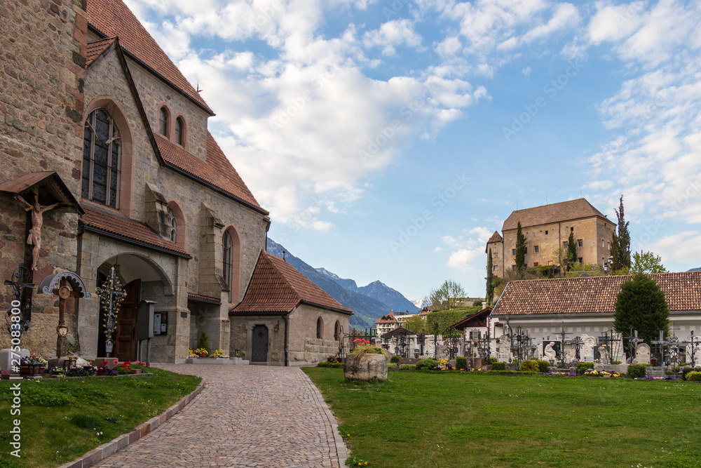 Entrance Square to Old Church, Alte Kirche, with Graveyard and Castle Schenna in the background. Scena, South Tyrol, Italy. Europe. Entrance Square to Old Church, Alte Kirche, with Graveyard and Castle Schenna in the background. Scena, South Tyrol, Italy. Europe.