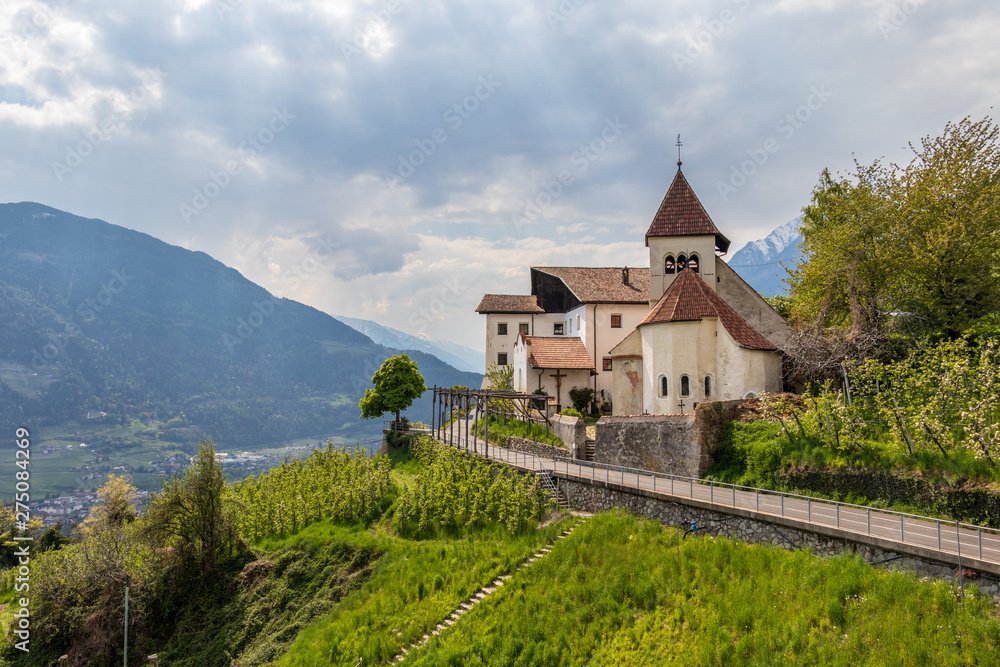 Panorama of Church Sankt Peter ob Gratsch, with mountains in the background in the municipality village of Tirol, South Tyrol, Italy. Europe.