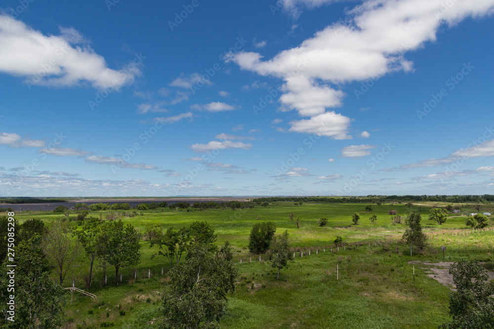Beautiful landscape of green valley with some trees, deep blue sky and white clouds