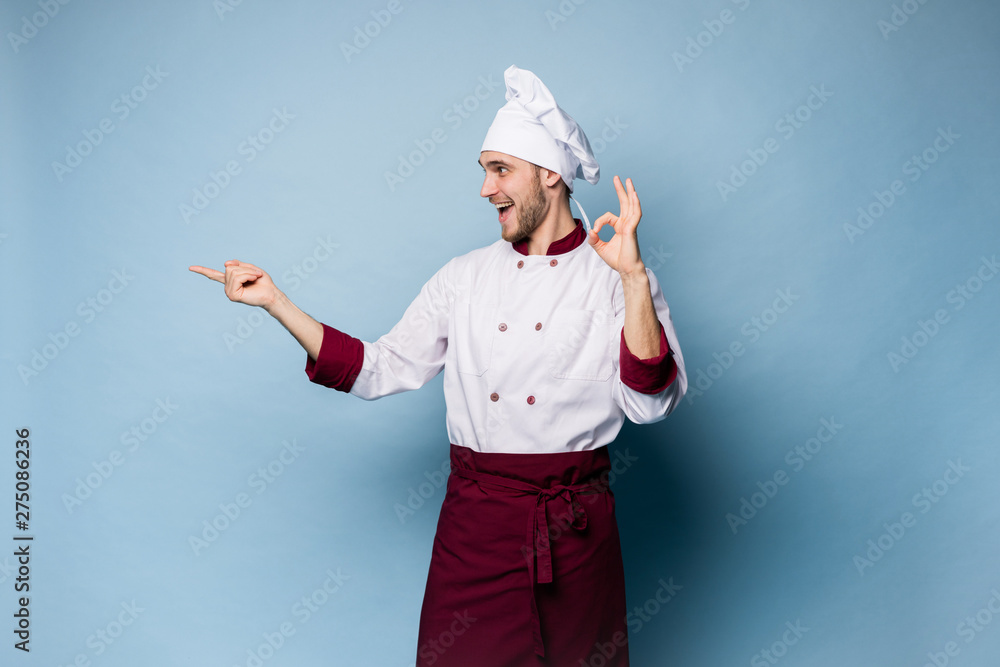 Positive professional happy man chef showing tasty ok sign isolated on light blue. Positive professional happy man chef showing tasty ok sign isolated on light blue.