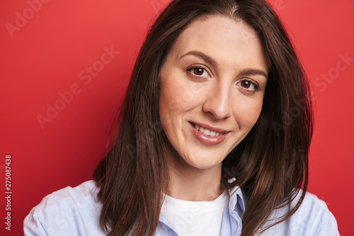 Happy young beautiful woman posing isolated over red wall background.