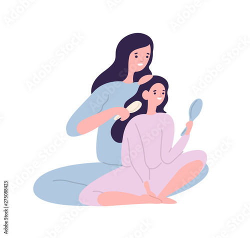Smiling mother brushing hair of daughter with hairbrush
