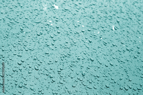 Water drops on car surface in cyan tone.