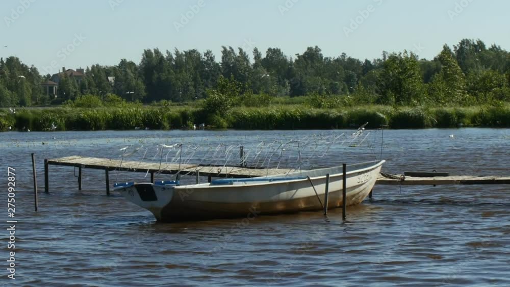 empty fishing boat moored in the old walkways on the shores of a picturesque lake empty fishing boat moored in the old walkways on the shores of a picturesque lake