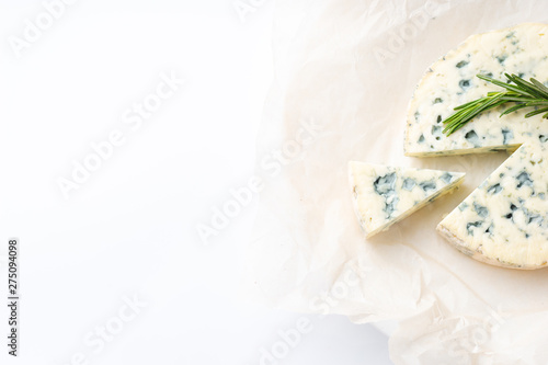 Slice of tasty blue cheese with rosemary on paper background