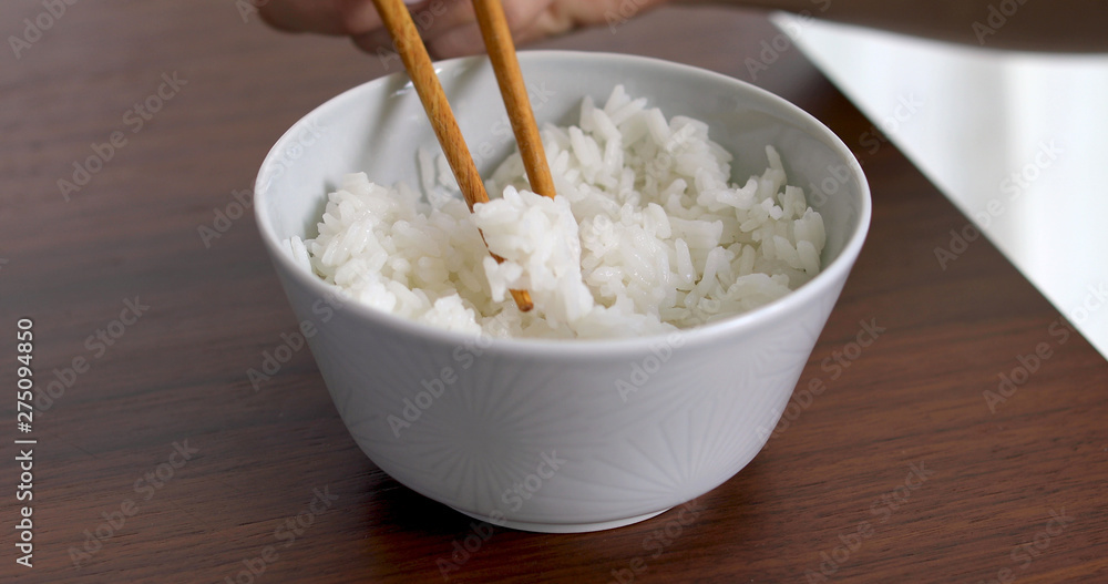 Closeup of woman eating rice from bowl with fork Closeup of woman eating rice from bowl with fork