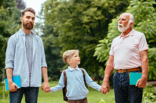 Family Generations concept: Father, son and Granddad, outdoors, in Nature, enjoying their Quality Time together, All in nice wear take child to school. © Iryna