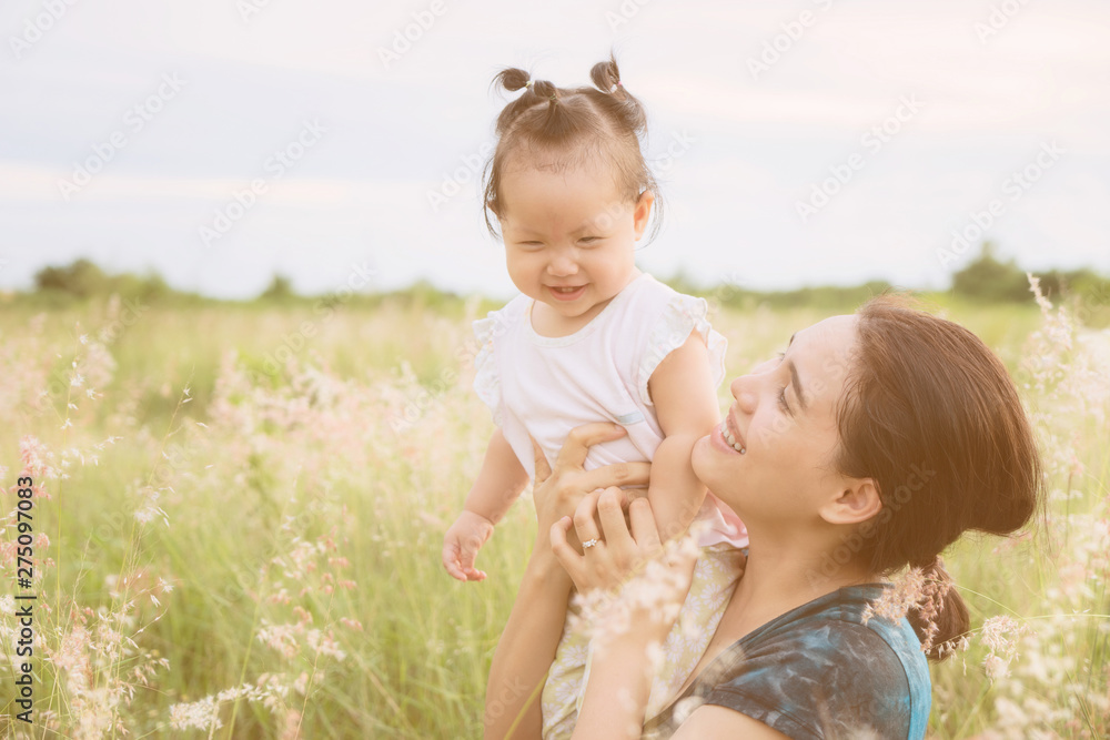 Asian young mother and daughter in the grass field at sunset. Asian young mother and daughter in the grass field at sunset.