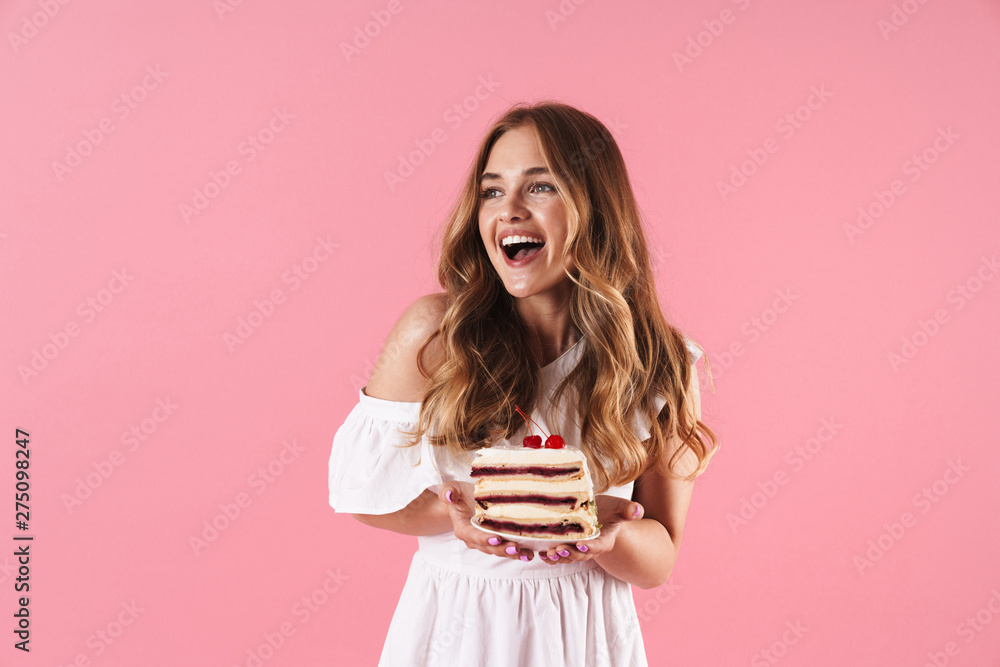 Image of happy smiling woman wearing white dress looking aside and holding piece of cake Image of happy smiling woman wearing white dress looking aside and holding piece of cake