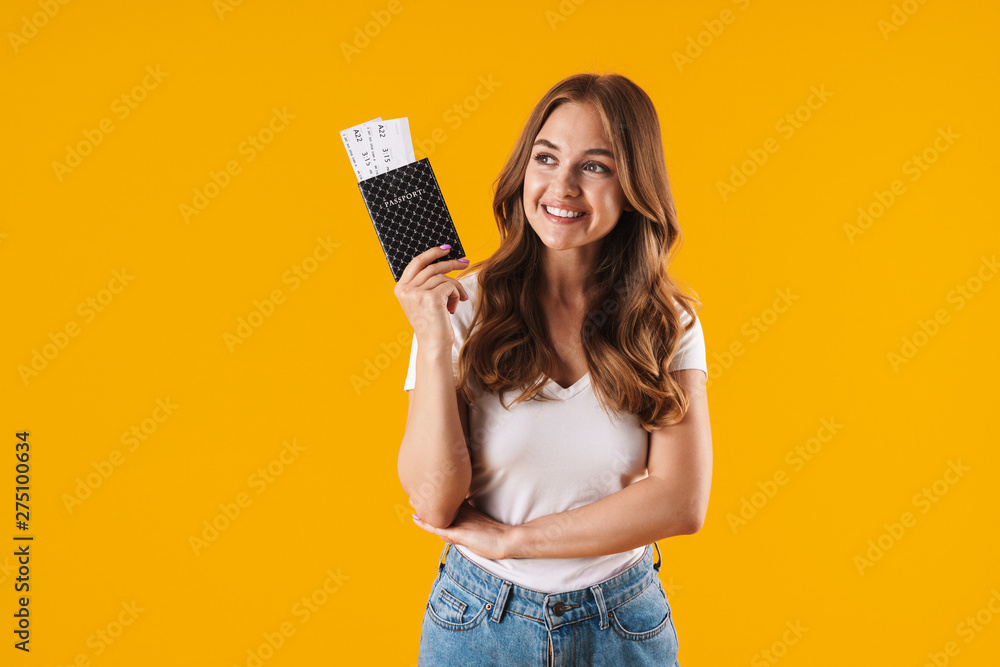 Photo of positive young woman smiling while holding passport and travel tickets - obrazy, fototapety, plakaty 