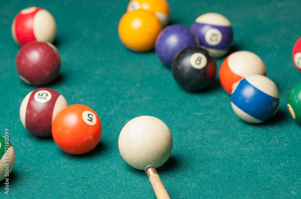 Naklejka premium Billiard balls and a stick on a green table. Billiard balls isolated on a green background