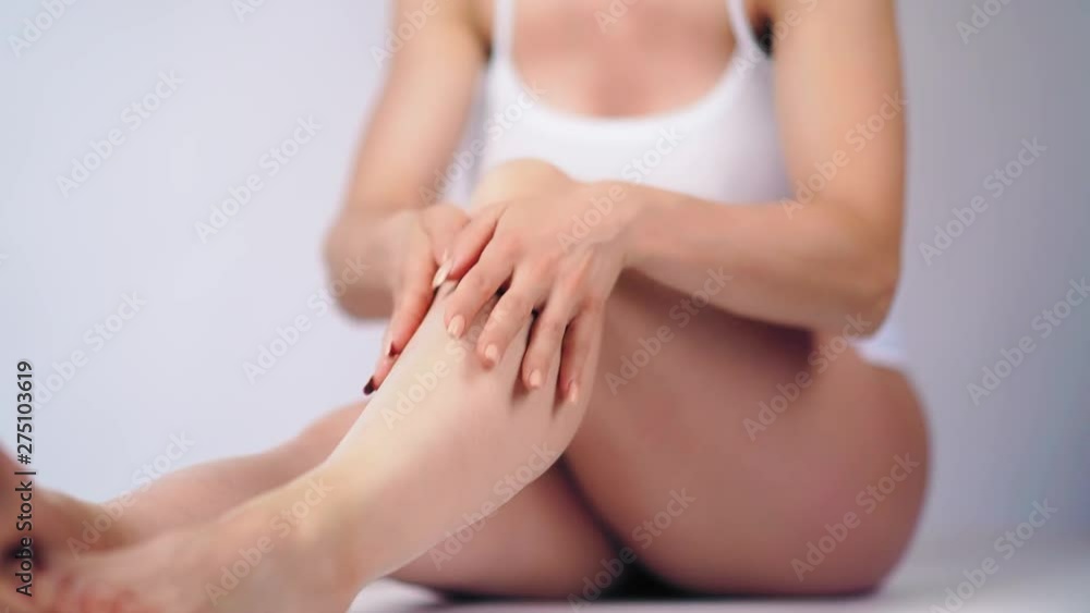 Woman applying moisturizer cream or body lotion on her legs. Concept of depilation, smooth skin, skincare and body Woman applying moisturizer cream or body lotion on her legs. Concept of depilation, smooth skin, skincare and body