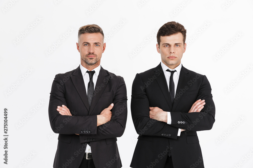 Image of masculine serious two businessmen in office suits looking at camera with arms crossed Image of masculine serious two businessmen in office suits looking at camera with arms crossed