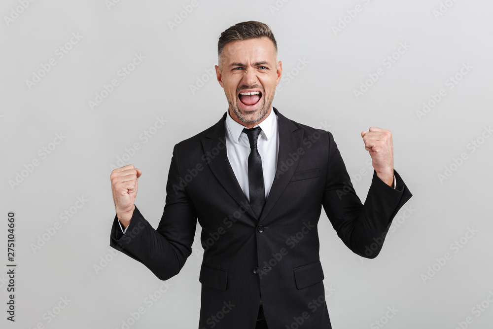 Image of successful delighted businessman in formal suit screaming and clenching his fists Image of successful delighted businessman in formal suit screaming and clenching his fists