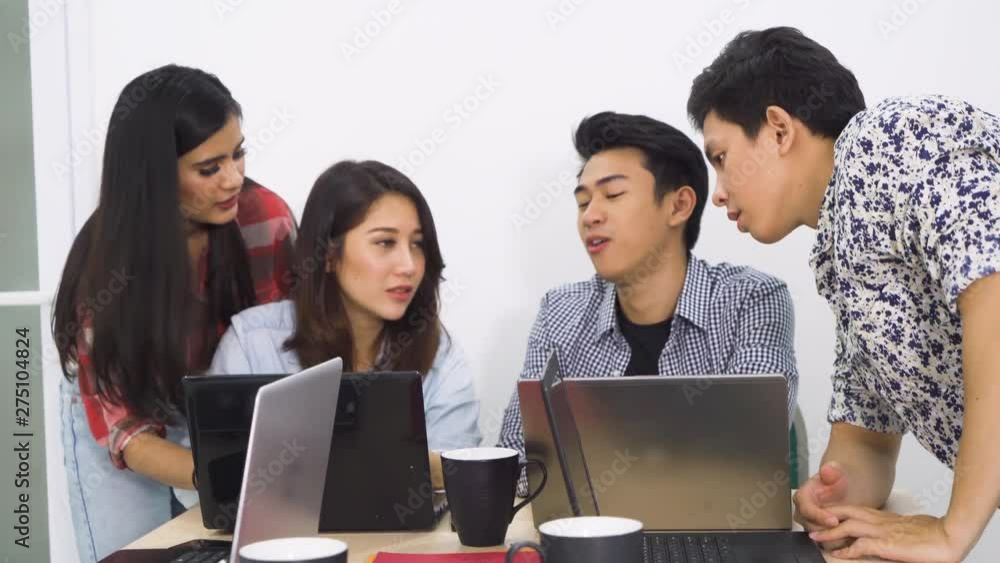 Young casual businesspeople discussing in office with laptop computer on the table. Shot in 4k resolution Young casual businesspeople discussing in office with laptop computer on the table. Shot in 4k resolution
