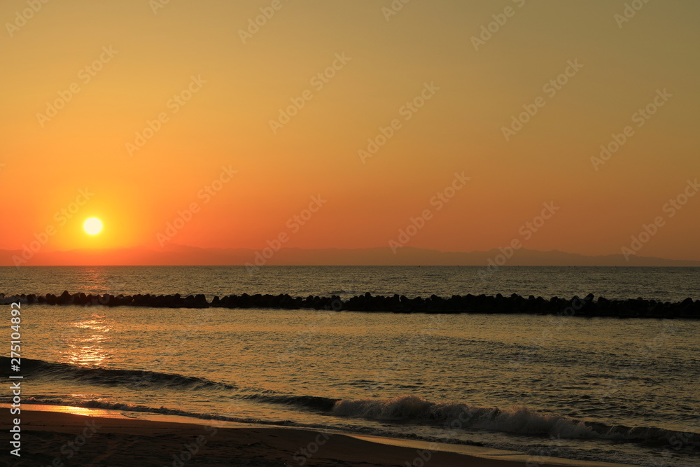新潟の日本海に沈む夕日と佐渡島の島影