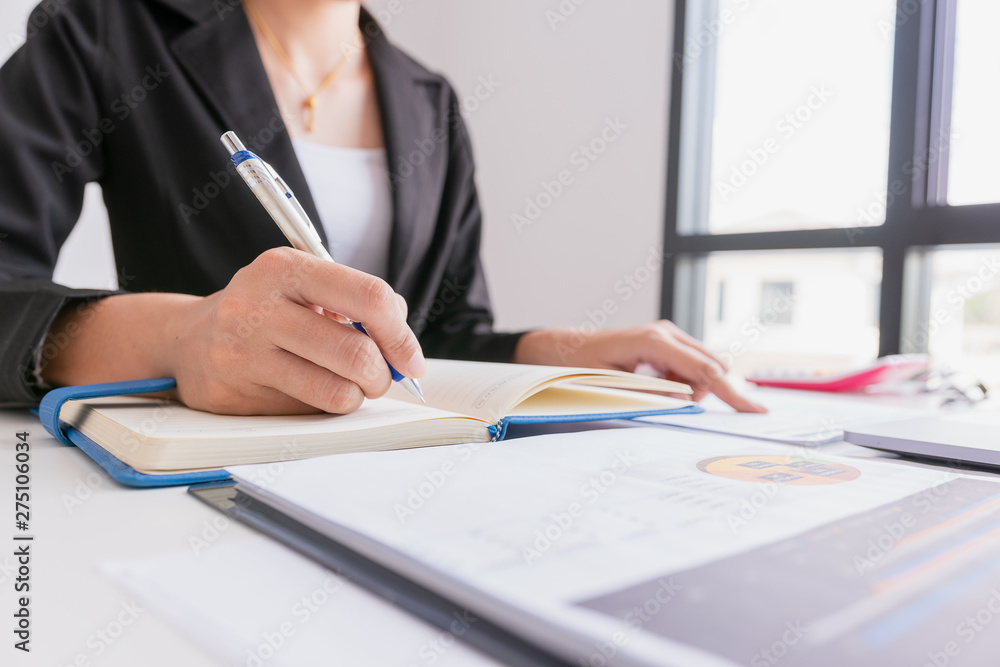 The woman is writing a message in the book on table. He is now sitting business plan that has new idea in the morning. Concept idea planing and analyzes. The woman is writing a message in the book on table. He is now sitting business plan that has new idea in the morning. Concept idea planing and analyzes.