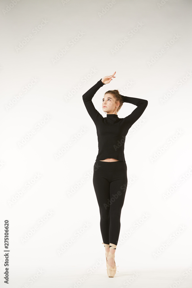 A girl in black clothes and Pointe shoes on a white isolated background performs dance and ballet poses and movements. A girl in black clothes and Pointe shoes on a white isolated background performs dance and ballet poses and movements.