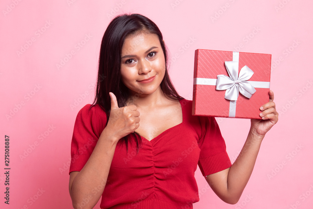 Young Asian woman thumbs up with a gift box. Young Asian woman thumbs up with a gift box.