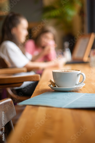 Cup of coffee and a menu with people in the background at a French Cafe