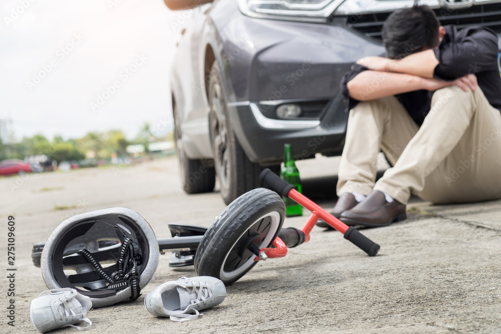 scared and stressed desperate drunken driver and bottle of beer in front of automobile crash car with child bike after traffic accident in city road scared and stressed desperate drunken driver and bottle of beer in front of automobile crash car with child bike after traffic accident in city road