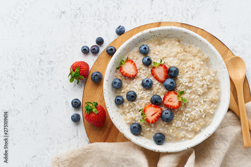 Oatmeal porridge rustic with berries, dash diet, on white wooden background top view photo