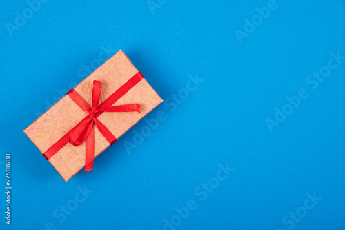 Gift box with red ribbon and bow on cyan blue background. 