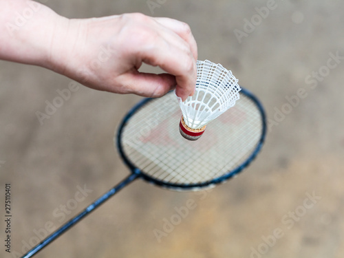 hand with white shuttlecock over badminton racquet