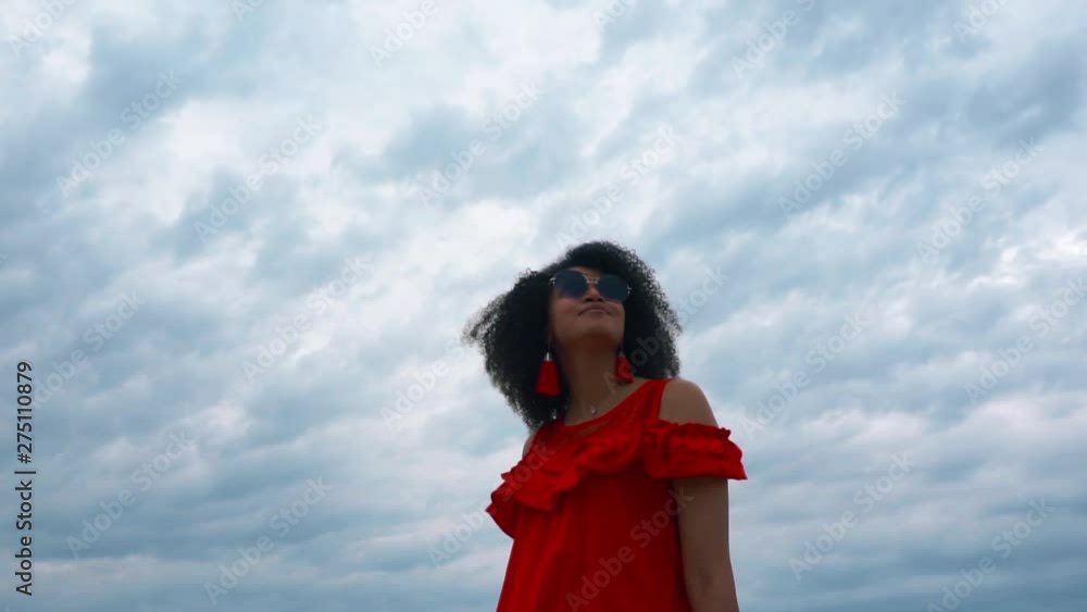Portrait of a beautiful African-american woman in red dress on sky background Portrait of a beautiful African-american woman in red dress on sky background