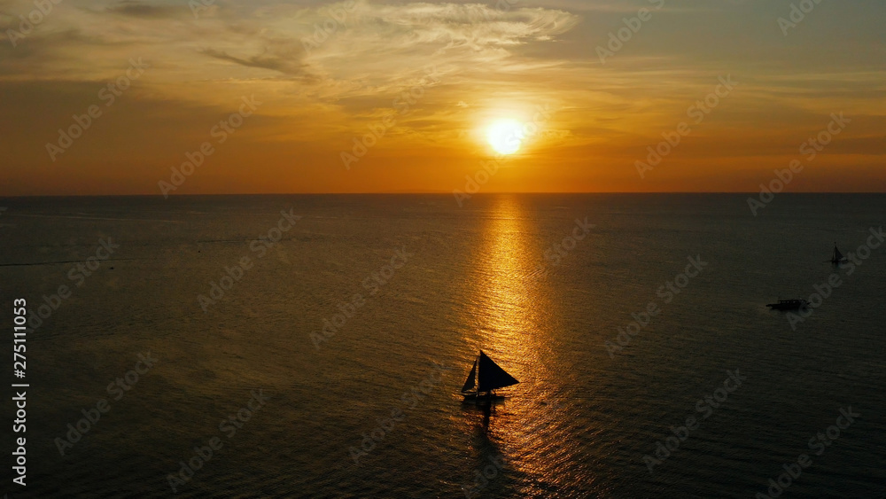 Colorful sunset above the sea surface with sailing yachts, aerial view Boracay, Philippines. Reflected sun on a water surface. Sunset over ocean. Seascape, Summer and travel vacation concept