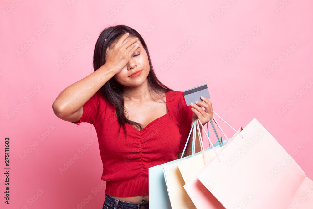 Unhappy young Asian woman with shopping bags and credit card. Unhappy young Asian woman with shopping bags and credit card.