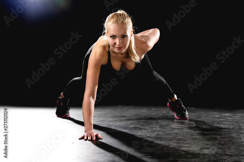 Sports girl performs pushups from the floor on one hand.