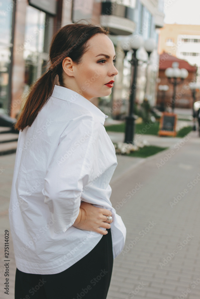 Serious brunette elegant woman business lady in white shirt at city street Serious brunette elegant woman business lady in white shirt at city street