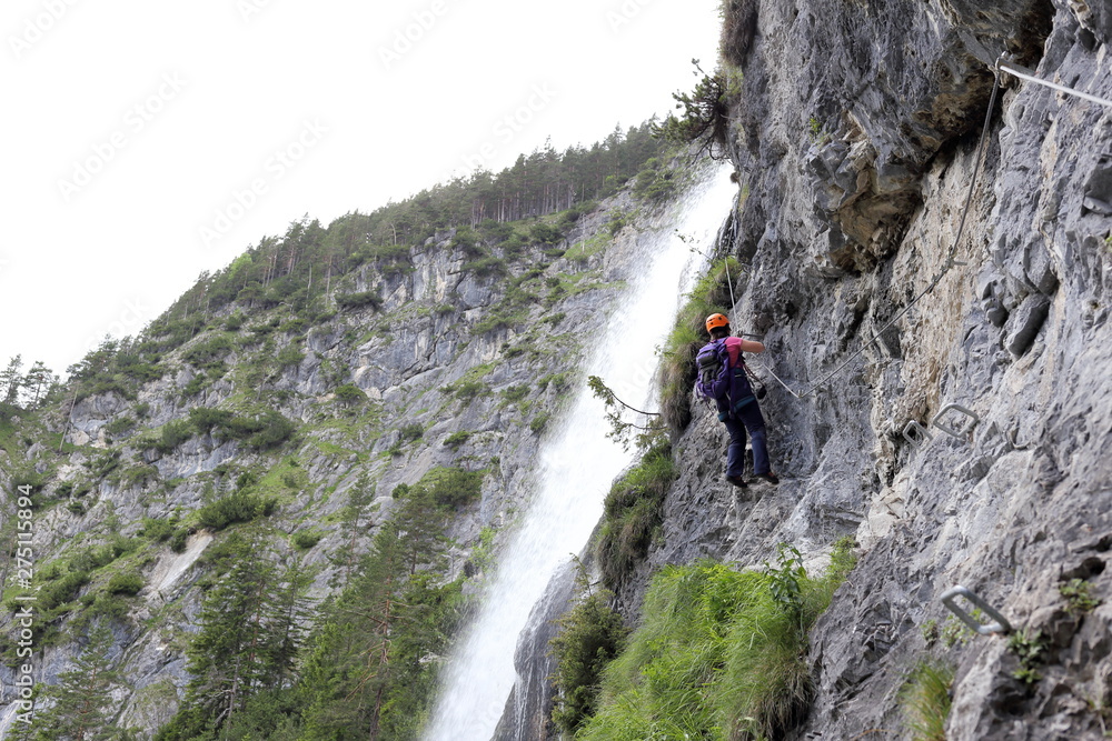 Frau klettert neben Wasserfall