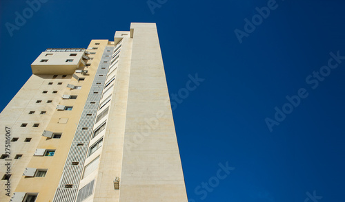 common high living building creative perspective foreshortening from below on blue sky background, copy space 
