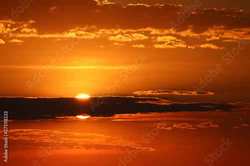 Sunset on orange sky  sun shining through the dark clouds. Beautiful skyline for background