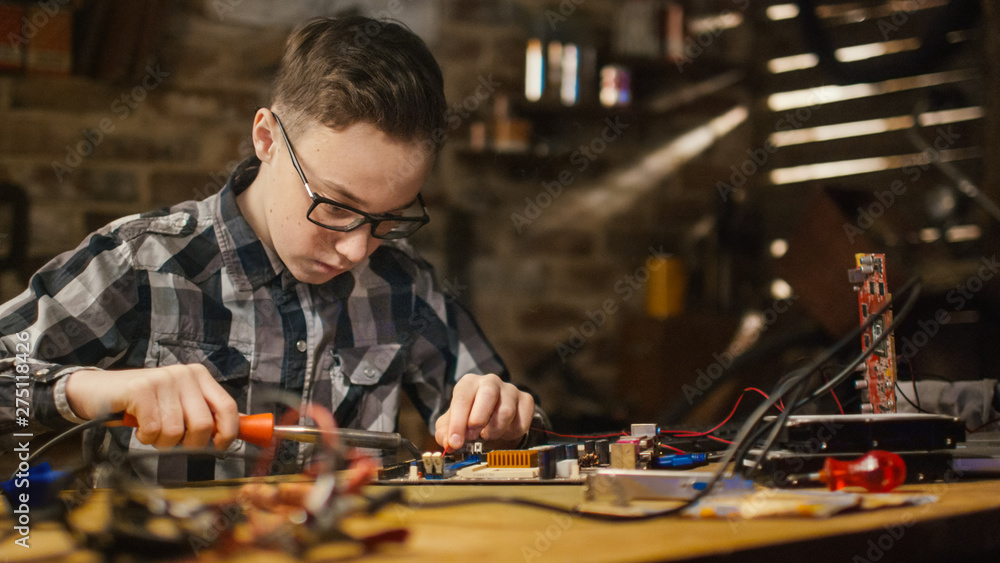 Portrait Shot of a Young boy is soldering a circuit board in a garage at home.