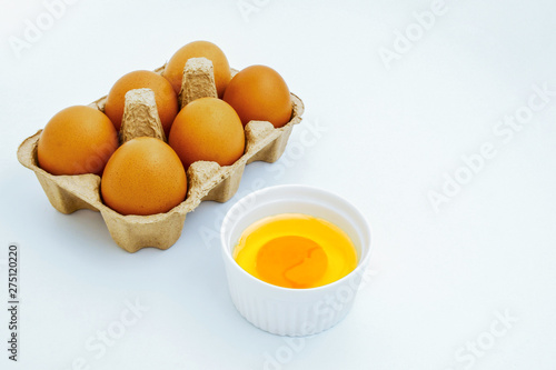 White egg and egg yolk on white background, top view. With copy area