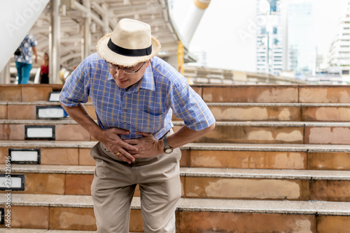 Asian old man, have an upset stomach, on the train station While he was traveling, to elder and health concept.