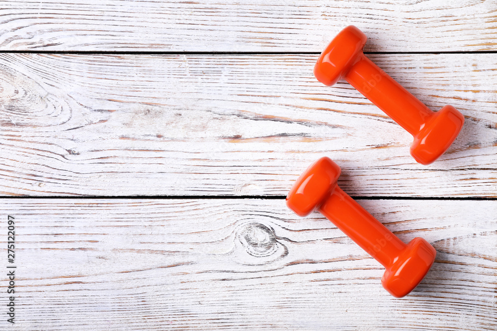 Bright dumbbells and space for text on wooden background, flat lay. Home fitness Bright dumbbells and space for text on wooden background, flat lay. Home fitness