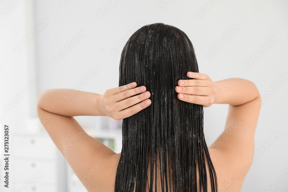 Woman applying hair conditioner in light bathroom Woman applying hair conditioner in light bathroom