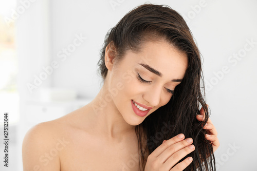 Beautiful young woman applying hair conditioner in bathroom