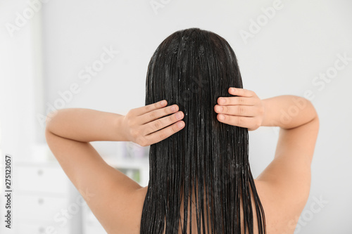 Woman applying hair conditioner in light bathroom