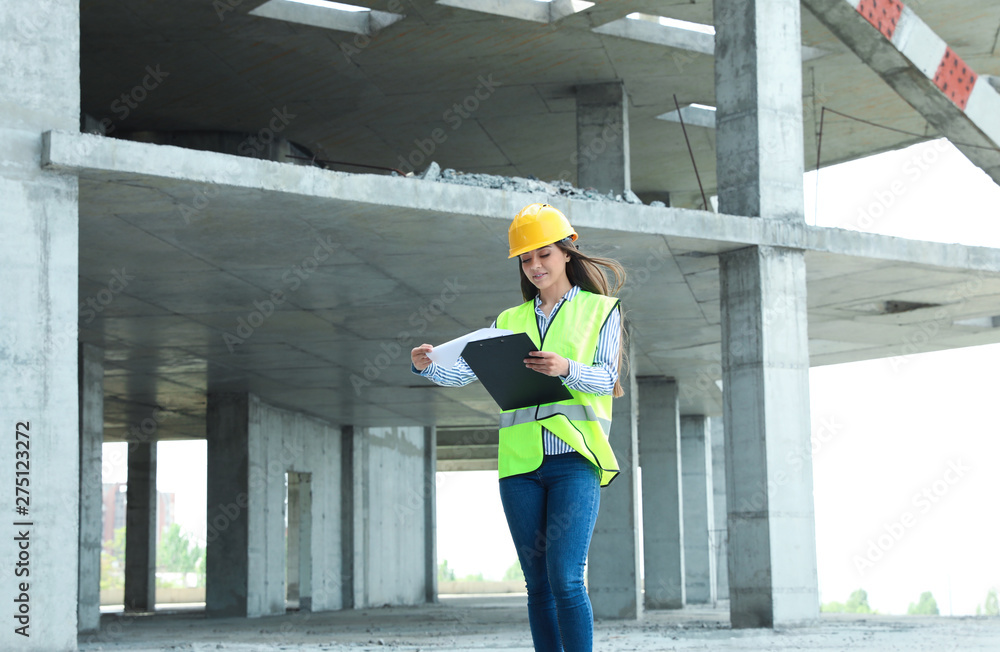Professional engineer in safety equipment with clipboard at construction site Professional engineer in safety equipment with clipboard at construction site
