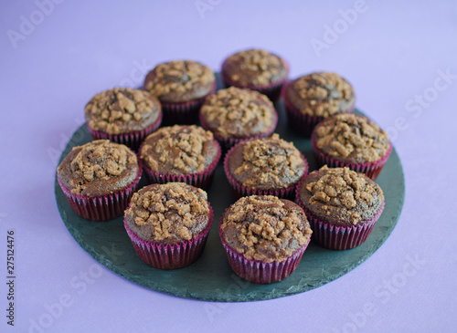 Set of chocolate muffins on black round board on purple background