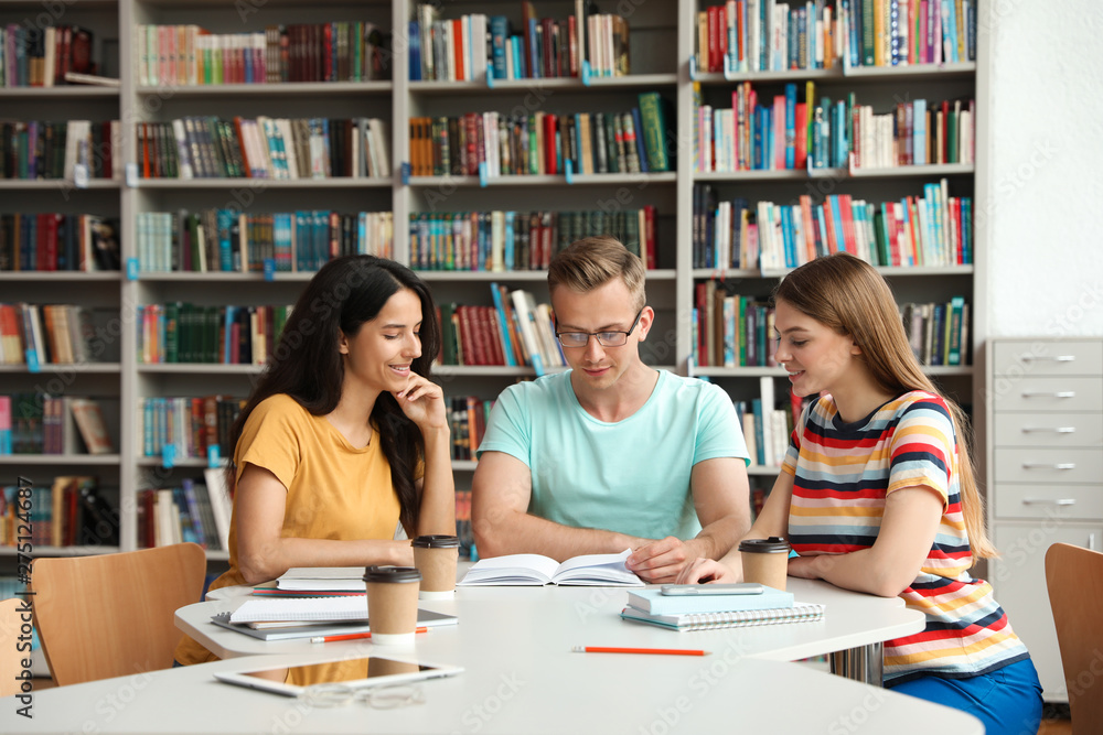 Young people discussing group project at table in library Young people discussing group project at table in library