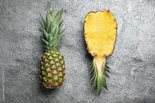 Fresh whole and cut pineapples on stone background, top view